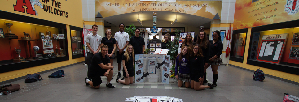 Students standing by cross in front lobby of high school