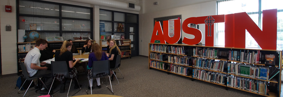 Students sitting in the library with Austin sign 