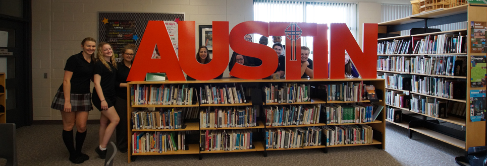 Students standing behind Austin sign - peaking through letters